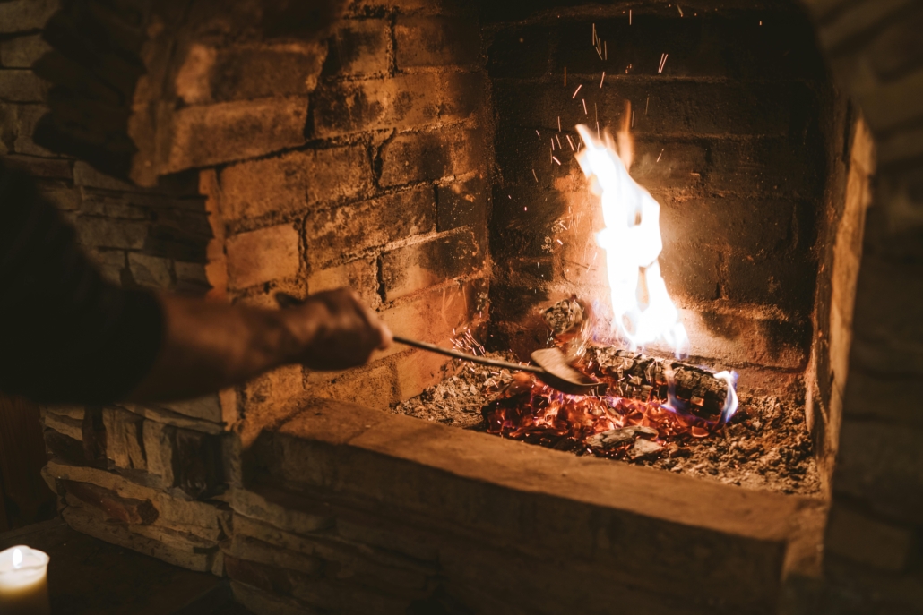 Man scooping piece of wood in brick fireplace